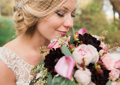 Beautiful bride smelling a bouquet of pink and red flowers