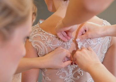 Helpers buttoning up back of bride's dress